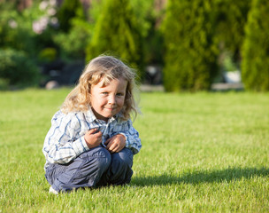  happy boy sitting on the green grass in sunny day 