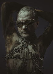 Fototapeta na wymiar bdsm, man with chains by the body and wire glasses, skin painted