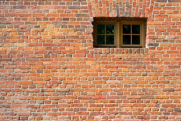 Small barred window in an old brick wall. The metal bars of the