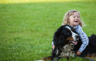 cute boy with curly blonde hair embraces a bernese mountain dog   © Tatiana Murr