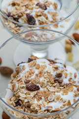 Granola with yoghurt, nuts and fruits in glass bowl on light background. Delicious, healthy sweet dessert for breakfast. Cereal, muesli. Copy space, closeup.