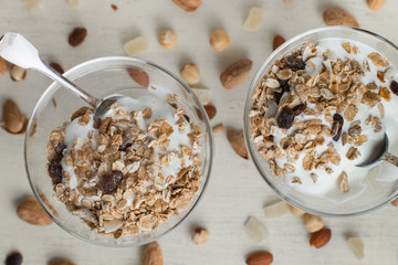Granola with yoghurt, nuts and fruits in glass bowl on light background. Delicious, healthy sweet dessert for breakfast. Cereal, muesli. Copy space, closeup.