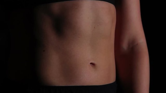 Young woman with ideal flat tummy breathing hard after active workout in gym