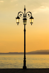 Obraz premium See - Uferpromenade mit Laternen bei Sonnenuntergang