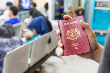 Hand holding Malaysia international  passport against bokeh crow