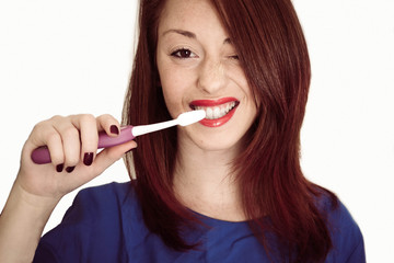 Portrait of a young and caucasian woman smiling with a toothbrush in her hand, isolated on white background- health, wellness and people concpet