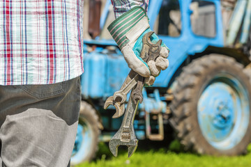 Fototapeta na wymiar Worker with adjustable wrench near the tractor