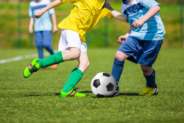 Training and football match between youth soccer teams. Boys kicking soccer football ball. Young soccer football players playing match at sports field