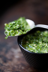 A spoon with basil and parsley pesto