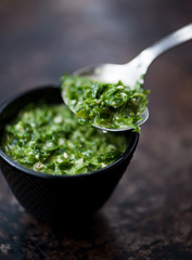 A spoon with basil and parsley pesto