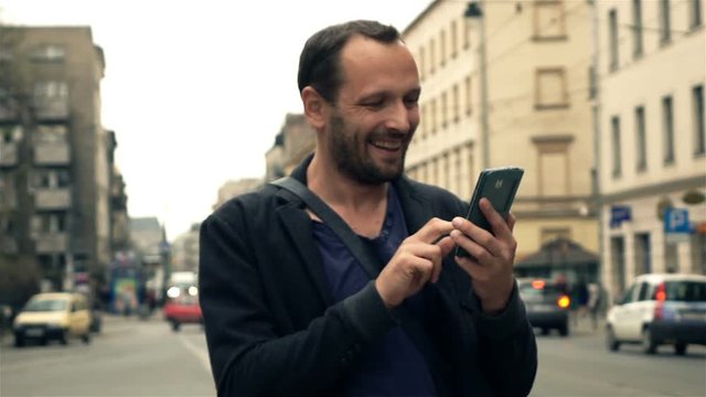Happy, young man using smartphone in city, super slow motion 240fps
