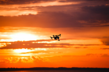 quadrocopter drone with remote control. Dark silhouette against colorfull sunset. Soft focus. Toned image