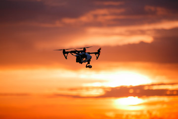 Fototapeta na wymiar quadrocopter drone with remote control. Dark silhouette against colorfull sunset. Soft focus. Toned image
