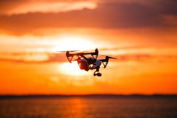 quadrocopter drone with remote control. Dark silhouette against colorfull sunset. Soft focus. Toned image