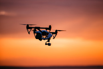 quadrocopter drone with remote control. Dark silhouette against colorfull sunset. Soft focus. Toned...