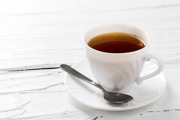Tasse Tee auf weißem Hintergrund aus Holz.