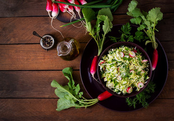 Vitamin salad of young vegetables: cabbage, radish, cucumber and fresh herbs. Top view