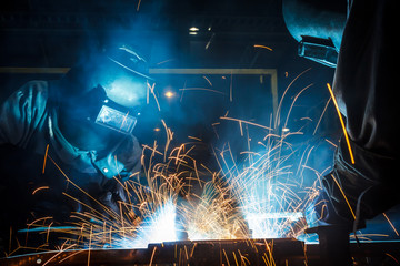 Team worker with protective mask welding metal