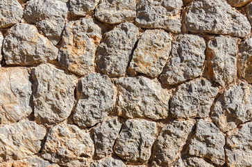 Ancient roughness stone wall.  Stonework of sandstone. Grey and golden texture. Can be used as background