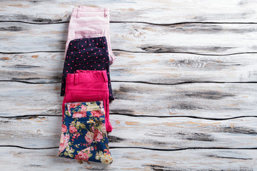 Folded trousers laying closely. Dark navy and floral pants. Good selection of girl's pants. Only authentic goods.