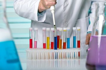 hand of a researcher pipetting samples in tubes test / Scientist in lab holding a 96 well plate with samples for analysis