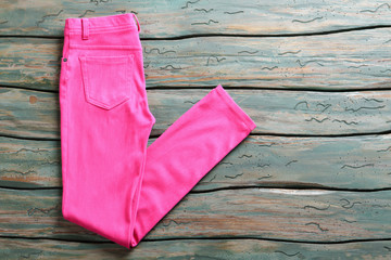 Pink casual pants. Folded trousers on wooden background. Woman's pants on green shelf. Garment bought at auction.