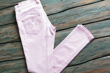 Light pink pants. Trousers on green wooden background. Brand new item on auction. Best price for quality merchandise.