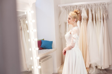 Happy future bride is doing try-on of gown