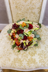 beautiful bouquet of colorful flowers and green roses lying on a chair close-up