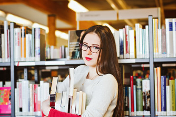 One Female student at the library holds books