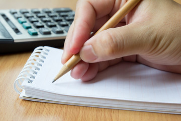 Calculator, notebook and pencil in hand for calculate
