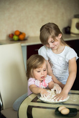 two children in the kitchen, child 2 years, child 7 years. child 2 years of a child 7 years old and their mother preparing breakfast in the kitchen.