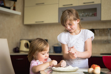 Obraz na płótnie Canvas two children in the kitchen, child 2 years, child 7 years. child 2 years of a child 7 years old and their mother preparing breakfast in the kitchen.
