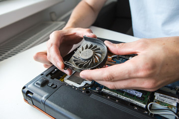 man blows dust into the laptop fan, laptop literacy repair men hands