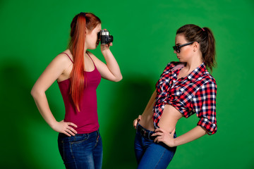 Two young women having fun posing and making photos with old cam