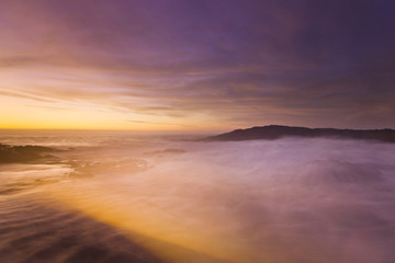 Fototapeta premium golden sunset at pacific ocean with waves on rocky shore