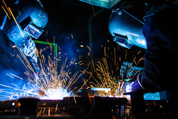 Teamworker with protective mask welding metal