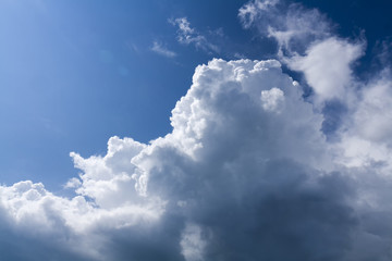 Naklejka na ściany i meble Edges of storm clouds illuminated by the sun on a background of blue sky