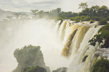 iguazu falls with green forest and stones surrounding