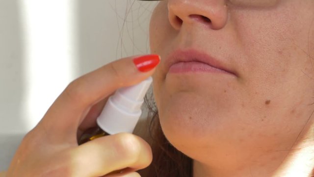 Woman is spraying medicine for throat treatment.