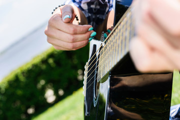 girl on a green meadow playing guitar