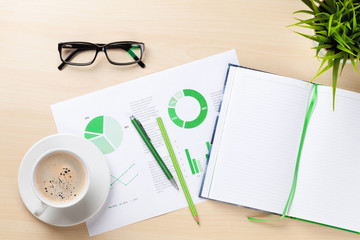 Office workplace with charts, plant and notepad