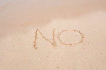 NO sign written in sand on beach texture sunny background. Closeup