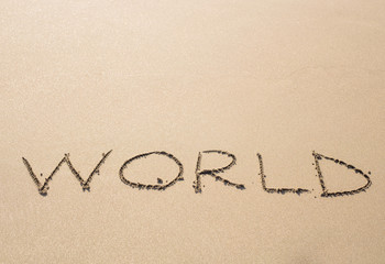 written word world on sand of beach