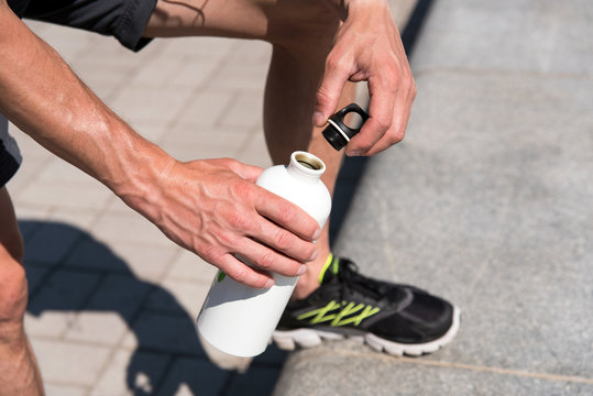 man opening bottle to drink water while training