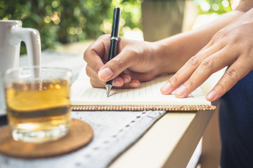 Writing outdoor in the garden with cup of tea © patpitchaya