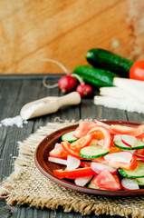 
healthy salad with fresh ripe summer vegetables , tomato, cucumber , radishes , spices and white toast on a wooden background