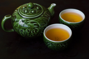 Green tea in two small cups and chinese traditional tea kettle