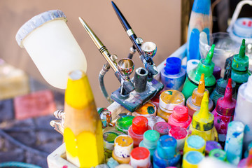 Professional airbrush on a stand with colorful paints in backgroung
