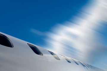 View of part of a rapidly flying passenger plane on a background of blue sky. From the outside